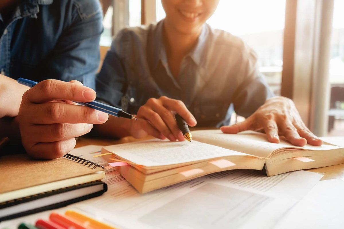 Two people study a book